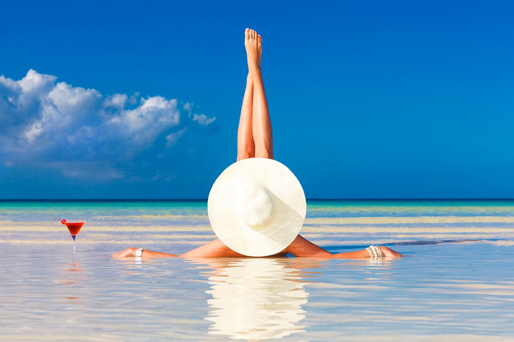 young woman in straw hat laying at the tropical beach and enjoyi